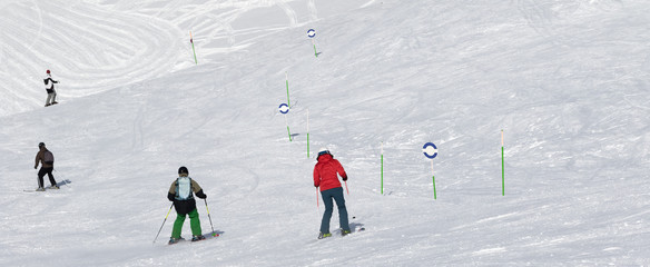 Skiers and snowboarders downhill on snowy ski trace