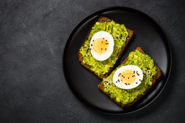 Avocado Sandwiches on black background.