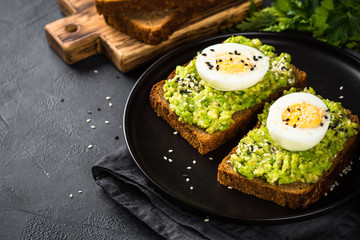 Avocado Sandwiches on black background.