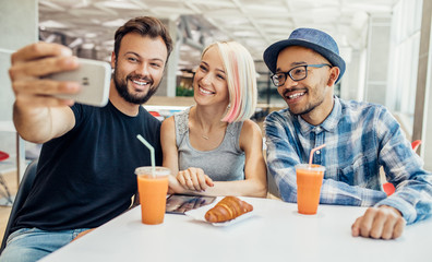 Multiethnic friends taking selfie in cafe