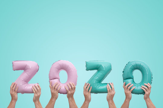 Hands holding numbers numbers 2020 made of pink and mint foil balloons on neo mint background. Greeting card to celebrate 2020 Happy New Year with copy space