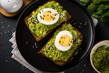 Avocado Sandwiches on black background.