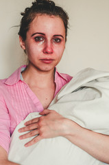 Young mother holds her newborn baby and cries because of post natal depression