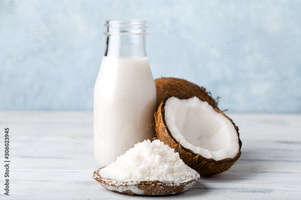 Wall mural coconut milk in a glass bottle, coconut flour in a plate, light background