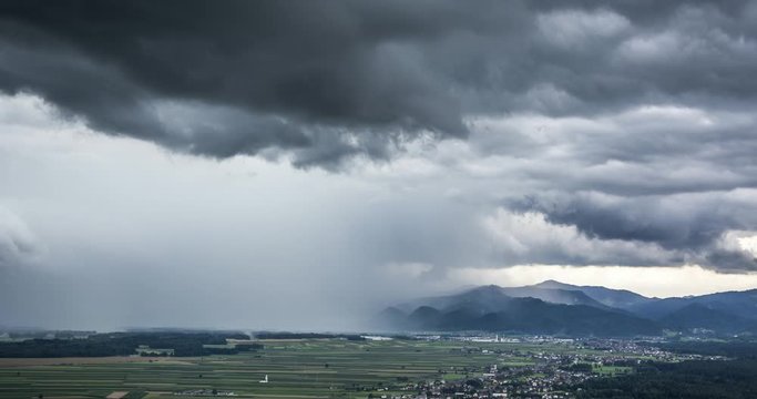 4k Time lapse of storm dark cloud rain pouring down on farming field town area