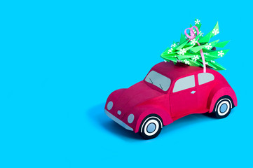 Red paper retro car carries Christmas tree