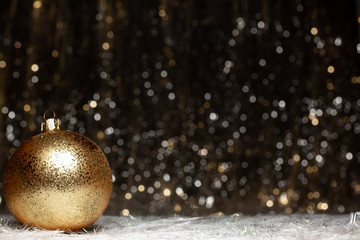 Christmas decorations composition view of gold evening ball with gold glitter on it of the left site on dark background with silver and gold colors bokeh. Holiday concept with copy space