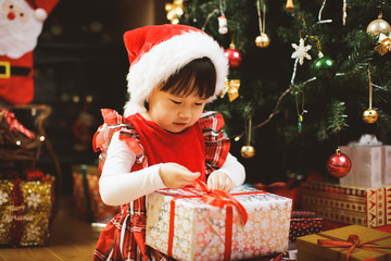 toddler girl getting christmas gift in front of christmas tree