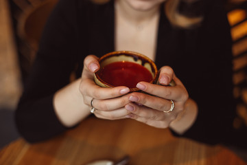 Red winter tea cup in female hands. Business woman warming her hands on a hot Cup of tea.