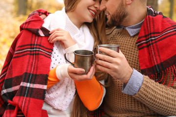 Loving young couple drinking hot tea in autumn park