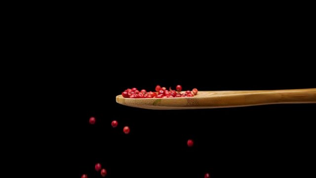 Red pepper in wooden spoon. Pepper is falling down in slow motion. Nobody in the frame.