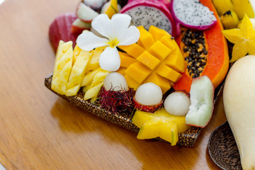 Juicy ripe tropical Thai fruits on a wooden dish.