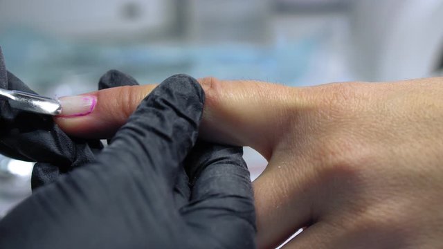 The procedure for removing gel polish from nails  in progress. Gel nail polish remover foils on woman's hands.