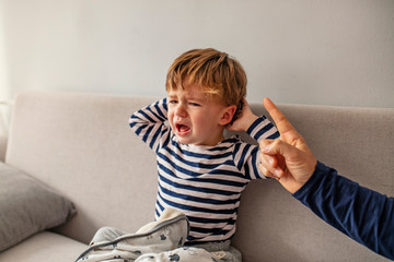 You are punished. Irritated father is yelling at his son. Strict father abuseshis son. Dad is raising a son. Little boy small child crying while some man is trying to reach him