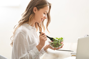 Woman eating healthy vegetable salad in office