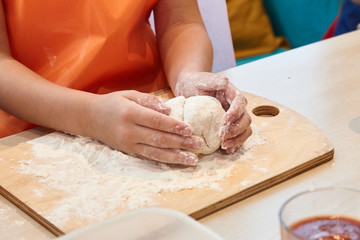 Fototapeta premium The kid 's learning to make pizza from the dough.