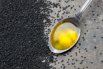 Black cumin seeds essential oil , Nigella Sativa in spoon on heap of black cumin. Organic herbal...