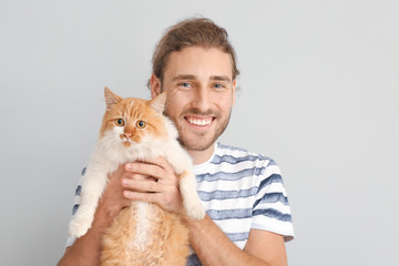 Man with cute cat on light background