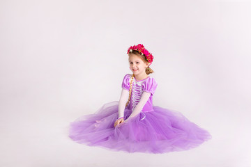 Fototapeta premium Little blonde girl wearing purple fairy princess dress on white background. Kids costume for new year party