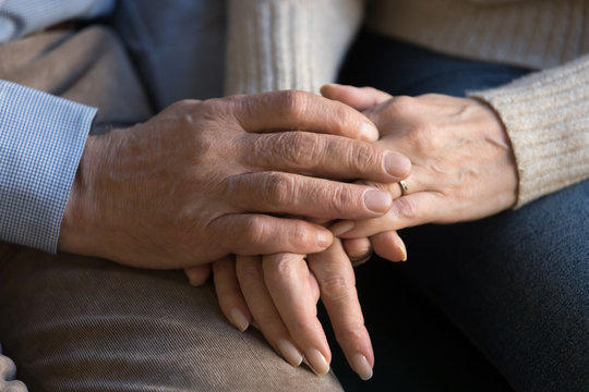 Close up image of elderly couple holding hands