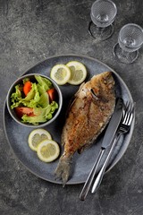 Grilled dorado with lemon, lettuce and tomatoes. Healthy food.