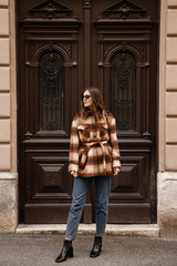 authentic street style portrait of an attractive woman wearing plaid check jacket coat, sunglasses...
