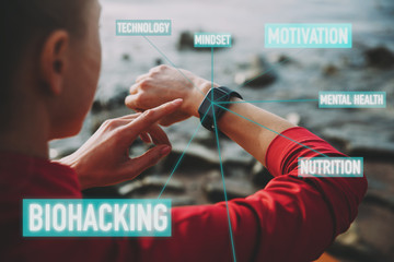 Concept of Biohacking, Modern Technology in Health and Sports. Woman Uses a Smartwatch on Her Hand to Train Healthy Lifestyle, View from behind