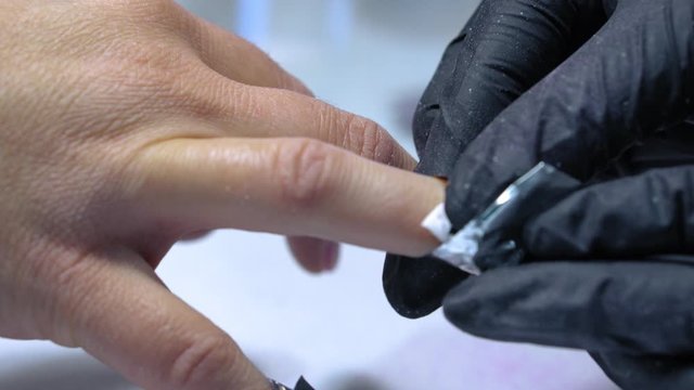 The procedure for removing gel polish from nails  in progress. Gel nail polish remover foils on woman's hands.