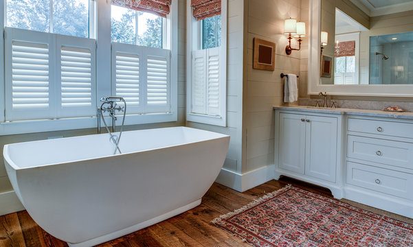 Luxury bathroom with large white tub, beautiful cabinets, and shiplap walls.