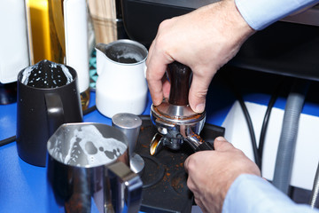Barista hands press freshly ground coffee