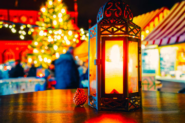 Street lamp with candle at Christmas Market at Gendarmenmarkt square in Winter Riga, Latvia. Advent Fair Decoration and Stalls with Crafts Items on the Bazaar. Latvian street Xmas and holiday