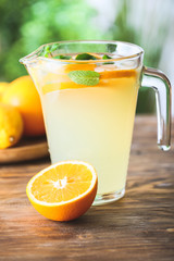 Jug of fresh lemonade on table outdoors