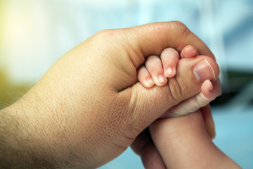 The baby grabs his father's finger for safety.
