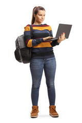 Female student standing and using a laptop