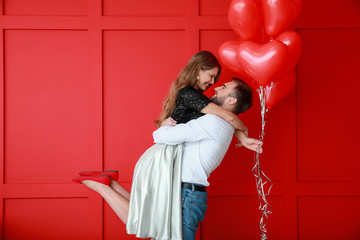 Happy young couple with heart-shaped balloons on color background. Valentine's Day celebration - obrazy, fototapety, plakaty