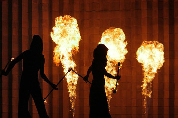 Silhouettes of men and women in the background of a stone wall and burning torches