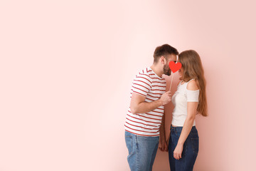 Happy young couple with red heart on color background. Valentine's Day celebration