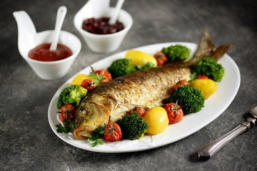 Baked carp fish with potatoes, cherry tomatoes and broccoli. Healthly food.