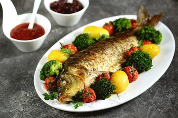 Baked carp fish with potatoes, cherry tomatoes and broccoli. Healthly food.
