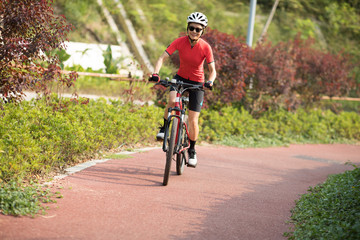 Fototapeta na wymiar Woman cyclist riding mountain bike in park