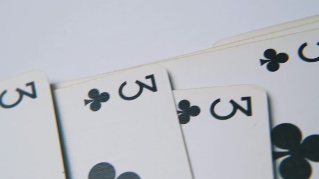 motion over line of black club playing cards lying on empty white surface extreme close view