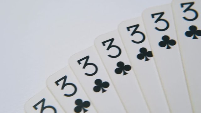 motion above fan of black club playing cards lying on clean white surface extreme close view