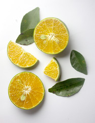 Group of fresh green citrus fruits and their leaves which have orange color inside and slice in different size and set in white color