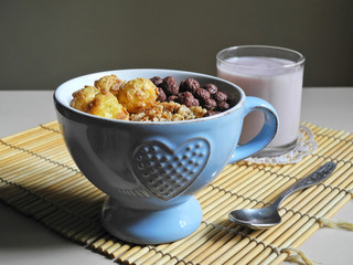 Corn balls and crunch in blue cup with heart texture and pink fruit yogurt in glass on background. Healthy breakfast.