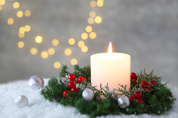Fototapeta na wymiar Burning candle with evergreen arrangment and christmas decoration,over gray with illuminaton background. 