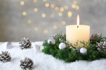 Obraz na płótnie Canvas Burning candle with evergreen arrangment and christmas decoration,over gray with illuminaton background. 