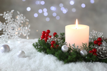 Burning candle with evergreen arrangment and christmas decoration,over gray with illuminaton background. 