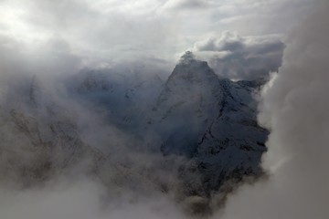 view on snowy mountains peak through clouds