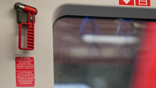 Emergency exit window in the wagons of the Moscow Central Ring MCC. Special red hammer for breaking a window in case of an accident. Public transport. Ring railway in the city.