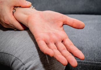Wrist pain. Medical and pharmaceutical concept. The woman is holding her wrist with her hand, feeling severe pain.